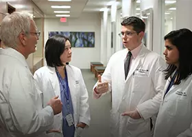 Regis O'Keefe, MD, PhD, and orthopaedic surgery residents talking in the hallway