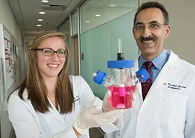 Farshid Guilak, PhD, and biomedical engineering PhD student Ali Ross, show a container with a prototype of a living hip replacement. 