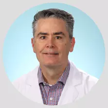 Photo of Dr. Jay Keener in a white lab coat on teal background